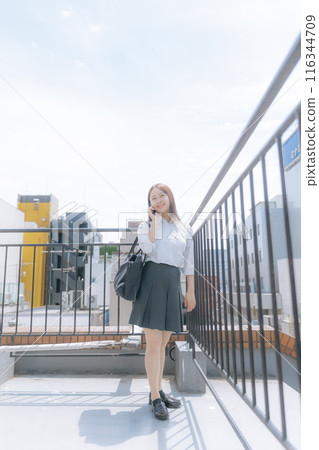 High school girl making a phone call on the rooftop 116344709