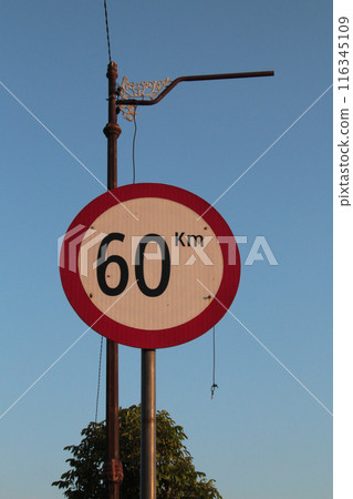 Road sign limiting speed to 60 km hour against blue sky in the morning Road sign limiting speed to 60 km hour against blue sky in the morning 116345109