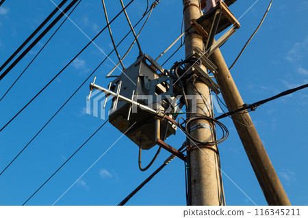 Electric post facing bright blue summer sky with blue sky background Electric post facing bright blue summer sky with blue sky background 116345211