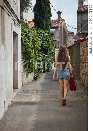 Woman walking in an alley, Southern Europe 116345535