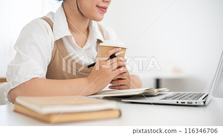 A cropped image of a woman working remotely from a coffee shop, reading something on her laptop. A cropped image of a woman working remotely from a coffee shop, reading something on her laptop. 116346706