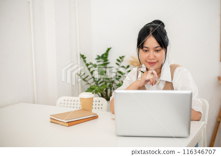 A beautiful Asian woman working remotely from a minimal white coffee shop, working on her laptop. A beautiful Asian woman working remotely from a minimal white coffee shop, working on her laptop. 116346707