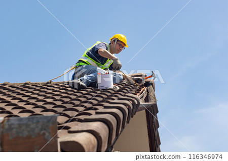 Worker man repairing eaves and tile of the old roof.. Worker man repairing eaves and tile of the old roof.. 116346974
