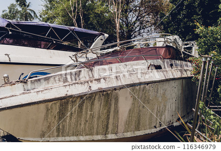 Old and rusty motor boats on a landfill surrounded by tropical forest 116346979