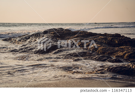 A large rocks surrounded by waves of the ocean A large rocks surrounded by waves of the ocean 116347113