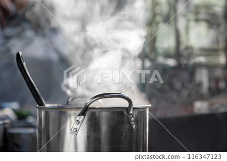 Steam over cooking pot in semi outdoor kitchen. 116347123