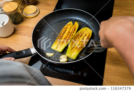 Chef at the kitchen preparing grilled eggplants with garlic 116347379