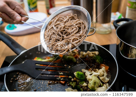 Chef at the kitchen preparing japanese buckwheat pasta with lentils Chef at the kitchen preparing japanese buckwheat pasta with lentils 116347599