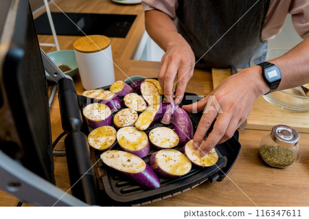 Chef at the kitchen preparing grilled eggplants with garlic 116347611