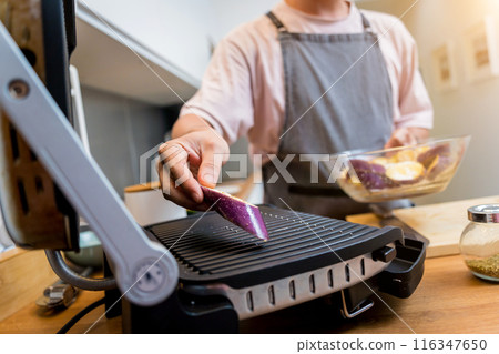 Chef at the kitchen preparing grilled eggplants with garlic 116347650