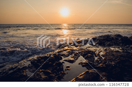 A large rocks surrounded by waves of the ocean A large rocks surrounded by waves of the ocean 116347728