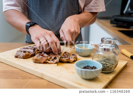 Chef at the kitchen preparing beef steaks on the home electric grill Chef at the kitchen preparing beef steaks on the home electric grill 116348169