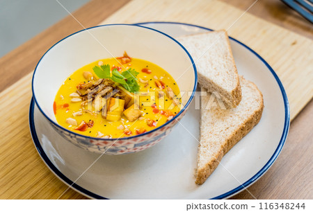 A bowl of pumpkin porridge with tofu and vegetables 116348244
