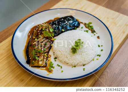 Delicious grilled eggplants with garlic on the white plate Delicious grilled eggplants with garlic on the white plate 116348252