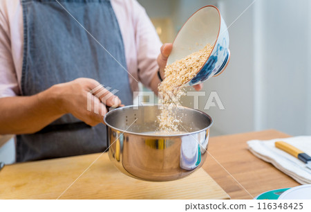 Chef at the kitchen preparing bowl of oats with strawberries and mango Chef at the kitchen preparing bowl of oats with strawberries and mango 116348425