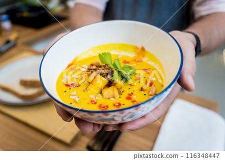 Chef at the kitchen preparing pumpkin porridge with tofu and vegetables 116348447