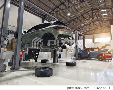 A car is raised up using a lift inside a service for maintenance A car is raised up using a lift inside a service for maintenance 116348891