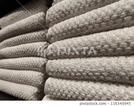 A stack of white towels neatly arranged on a black shelf 116348945