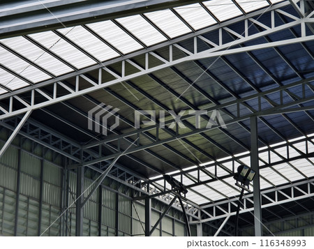 A large building with metal roof against a cloudy sky 116348993