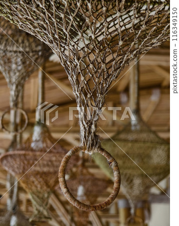 Elegant wicker lamp suspended from a rustic wooden ceiling 116349150