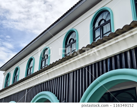 White building with arched windows, blue trim, stands tall under clear sky White building with arched windows, blue trim, stands tall under clear sky 116349152