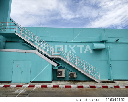 Metal stairs to blue building against sky and clouds Metal stairs to blue building against sky and clouds 116349162