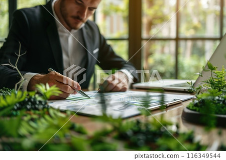A man in a suit is writing on a piece of paper with a pen 116349544