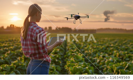 A woman is standing in a field with a drone flying above her 116349569