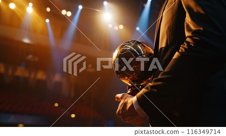 A man is holding a gold soccer ball in his hand 116349714