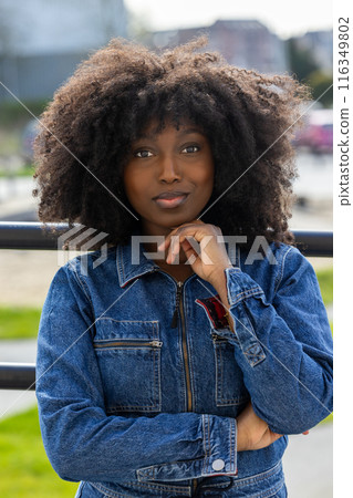Confident African American woman in denim jacket with curly hair outdoors portrait Confident African American woman in denim jacket with curly hair outdoors portrait 116349802