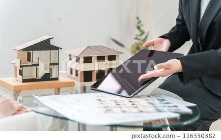 The hands of a businesswoman proposing home renovations while looking at a tablet, blueprints, and drawings 116350382