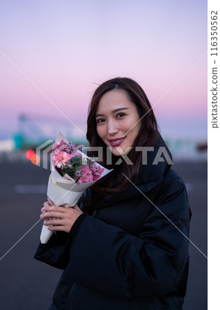 A woman holding a bouquet in the park at sunset A woman holding a bouquet in the park at sunset 116350562