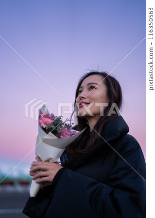 日落時公園裡拿著一束花的女人 116350563