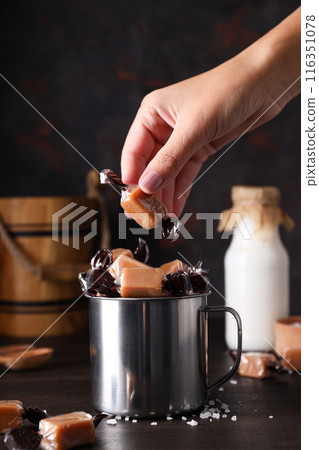 Cubes of salted caramel in a metal cup with milk in a bottle Cubes of salted caramel in a metal cup with milk in a bottle 116351078
