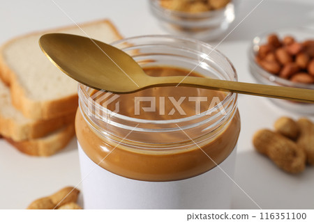 Peanut paste in a glass jar with a spoon, on a light background. Peanut paste in a glass jar with a spoon, on a light background. 116351100