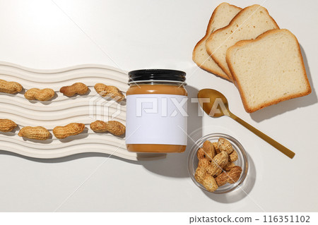 Peanut paste in a glass jar with a spoon, on a light background. Peanut paste in a glass jar with a spoon, on a light background. 116351102