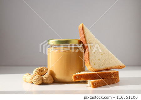 Peanut paste in a glass jar, on a light background. 116351106