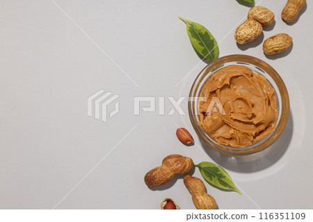 Peanut paste in a transparent plate, on a light background. Peanut paste in a transparent plate, on a light background. 116351109