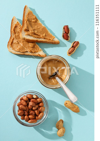 Peanut paste in a glass jar with toast, on a light background. 116351111