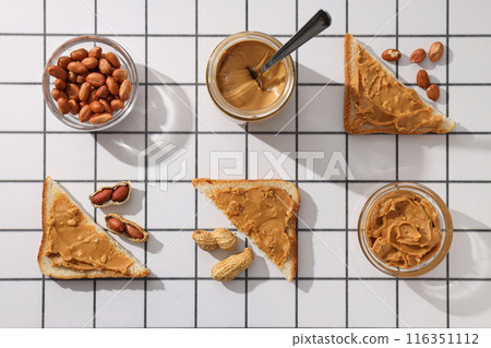 Peanut paste in a glass jar with a spoon, on a light background. Peanut paste in a glass jar with a spoon, on a light background. 116351112