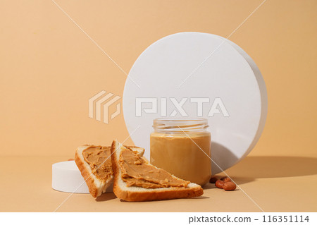 Peanut paste in a glass jar with toast, on a light background. 116351114