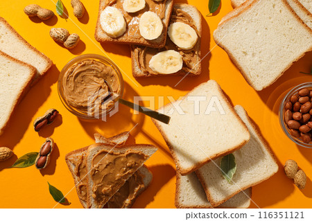 Peanut paste in a jar with sandwiches next to it on a yellow background. Peanut paste in a jar with sandwiches next to it on a yellow background. 116351121