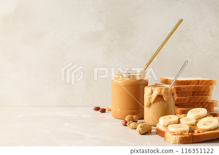 Peanut paste in a glass jar, on a light background. Peanut paste in a glass jar, on a light background. 116351122