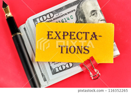 inscription Expectations word on a yellow piece of paper on dollars on a red background 116352265