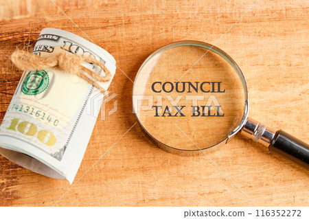 COUNCIL TAX BILL word through a magnifying glass with American dollars lying next to it COUNCIL TAX BILL word through a magnifying glass with American dollars lying next to it 116352272