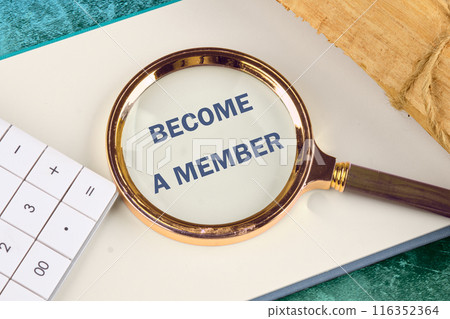 The inscription BECOME A MEMBER appeared through a magnifying glass in a notebook, close-up. View from above. 116352364