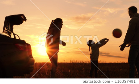 Family playing with ball near car at sunset, silhouettes. Father, mother, daughter throwing ball in circle, laughing, having fun joyful good time in field, creating pleasant unforgettable memories. Family playing with ball near car at sunset, silhouettes. Father, mother, daughter throwing ball in circle, laughing, having fun joyful good time in field, creating pleasant unforgettable memories. 116357491