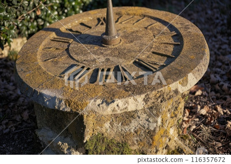 A close-up of an ancient sundial with shadows indicating the time, set in an old garden, symbolizing the timeless connection between nature and time A close-up of an ancient sundial with shadows indicating the time, set in an old garden, symbolizing the timeless connection between nature and time 116357672
