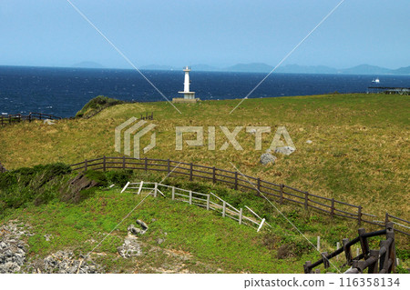 Yobuko, Karatsu City "Suginohara Pasture" on Kabe Island. A white lighthouse and the blue waters of the Genkai Sea. Yobuko, Karatsu City "Suginohara Pasture" on Kabe Island. A white lighthouse and the blue waters of the Genkai Sea. 116358134
