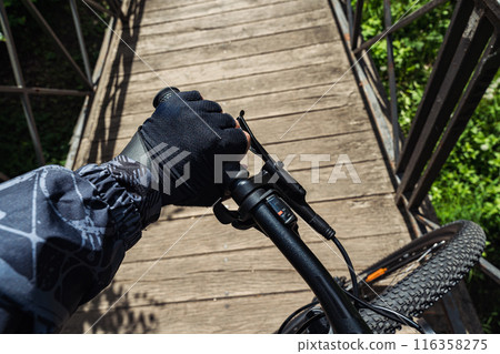 Mtb biking background with fragment of biker hand holding bicycle handlebar. First person view. 116358275